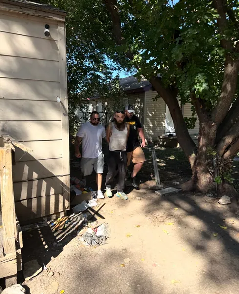 People outside a house beside a shaded walkway.