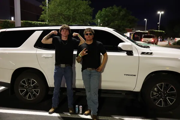 Two people beside a white SUV at night.