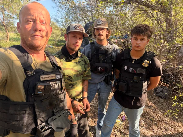 Four people photographed together in a wooded area.