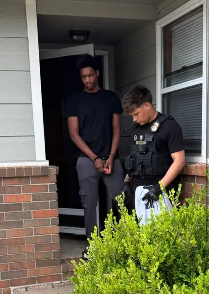 Two people outside a brick-front residence.