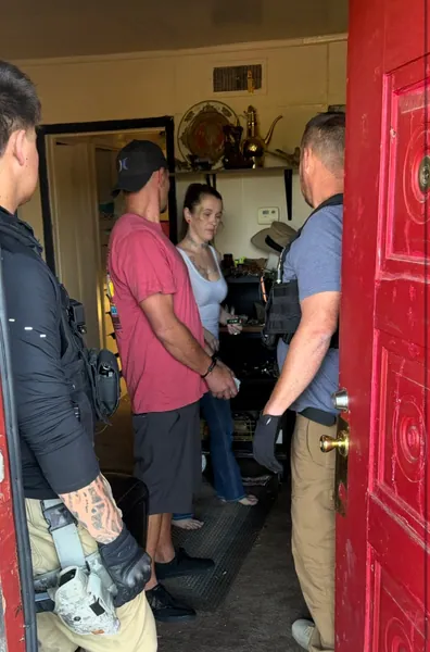 People standing just inside an open red front door.