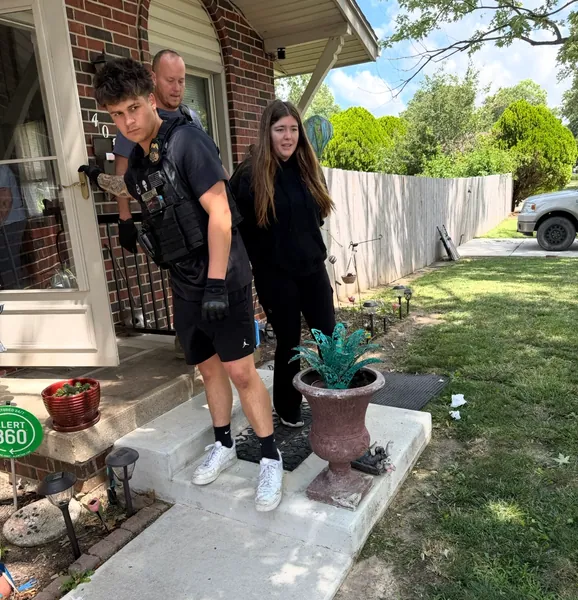 Two people on the steps of a brick-front home.