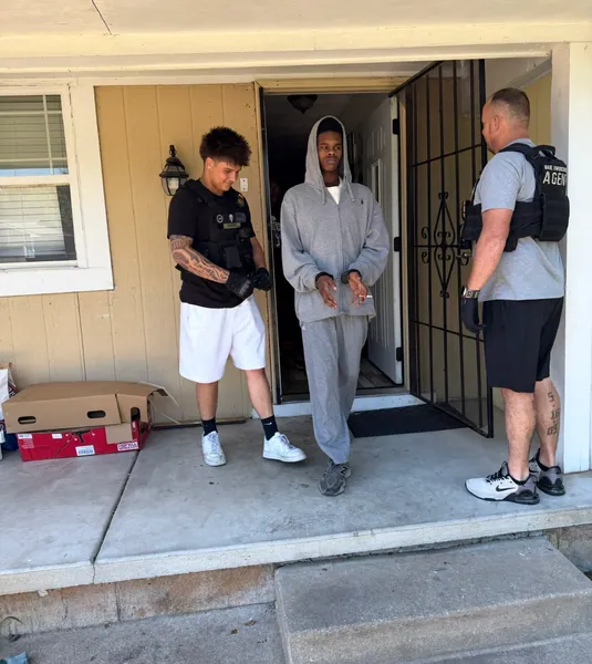 Three people standing on a covered porch.