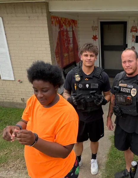 Three people standing on a lawn outside a home.