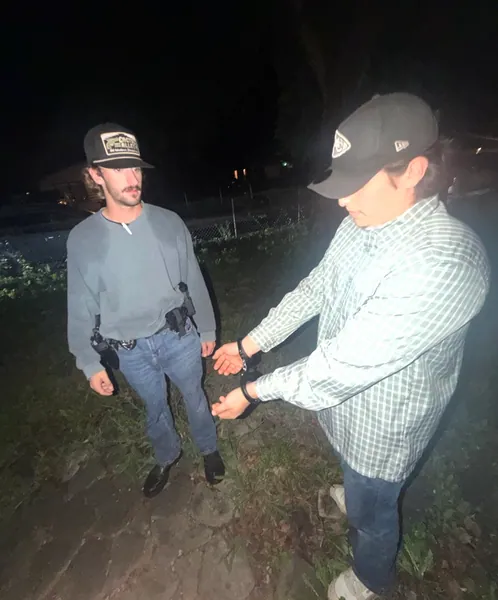 Two people standing outdoors on grass at night.