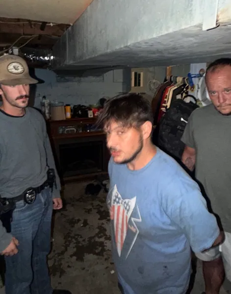 Three people standing in a dimly lit room.