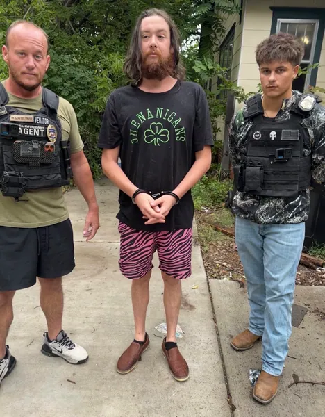 Three people standing together outdoors in daylight.