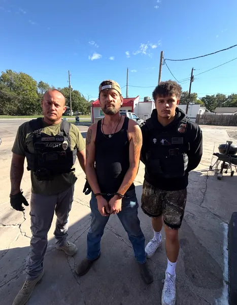 Three people standing outdoors near a street.
